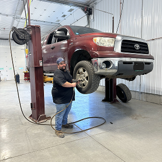 person working on lifted car | Don's Auto Service Inc